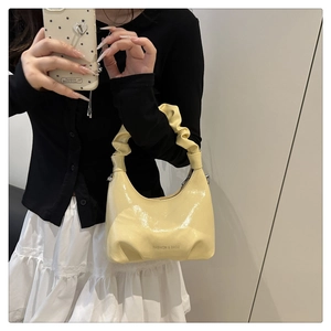 Close-up of vibrant yellow pleated dumpling bag featuring high-shine glossy leather finish