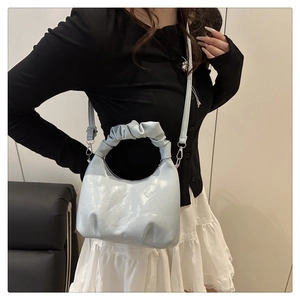 Detail of light blue cloud-shaped handbag with glossy finish and thin shoulder strap