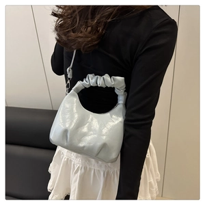 Detail shot of the ruffled strap and light blue pleated cloud bag worn by a model