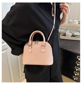Close-up of pink shell-shaped crossbody bag with woven texture and top zip closure