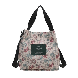 Floral canvas tote bag with black straps and adjustable shoulder strap on white background