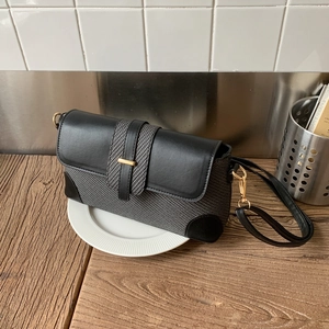 Détail du tissu gris tissé et du cuir noir avec boucle dorée sur le sac à main