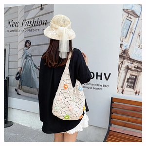 Detail of hand-woven beige knit bag featuring multi-color 3D floral accents for summer