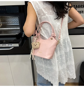 Pink bucket bag detail with plush bear charm and silk scarf on smooth synthetic leather