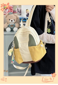 Detail of color-block canvas backpack with side drawstring pocket and cute bear charm