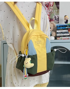 Detail of colorful nylon backpack featuring drawstring closure and moon plush keychain