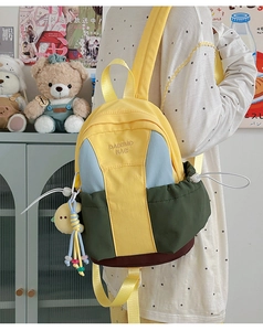 Detail of color-block backpack with logo embroidery and plush chick pendant accessory