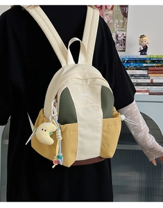 Detail of color-block backpack with drawstring pockets and yellow moon plush charm