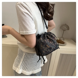 Detail of vintage floral drawstring bucket bag with gold pattern and slim leather strap