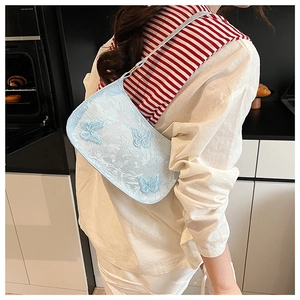 Dettaglio della borsa sottobraccio celeste con farfalle 3D e trama in tessuto jacquard