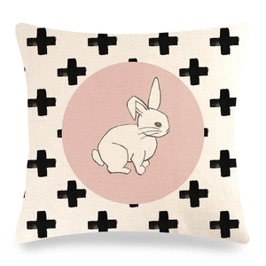 Detail of linen Easter pillow cover with black cross pattern and pink rabbit silhouette