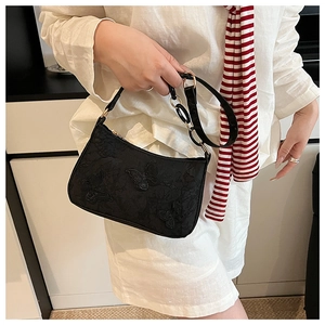 Close-up of black shoulder bag featuring 3D butterfly embroidery and elegant silk texture