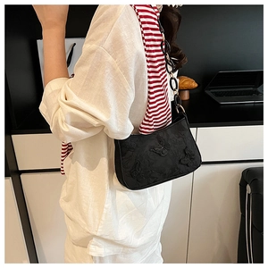 Detail of black canvas tote bag featuring floral embroidery and acrylic chain strap