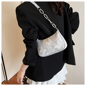 Detail of white butterfly lace embroidery and chain strap on hobo shoulder bag