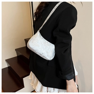 Detailed embroidery of elegant white butterfly patterns on a sleek silk shoulder bag