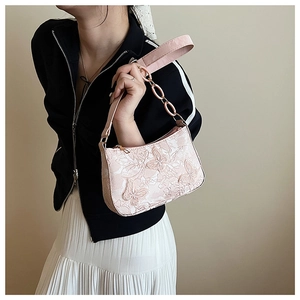 Close-up of pink shoulder bag with 3D butterfly embossing and metal chain strap