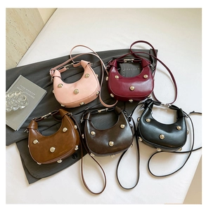Flat lay of five hobo mini bags in various colors with metallic punk studs and slim straps