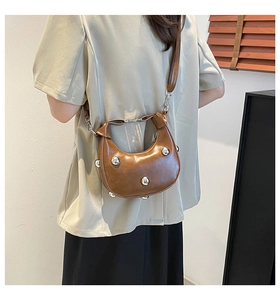 Back view of model wearing a brown crescent bag with silver studs and leather strap