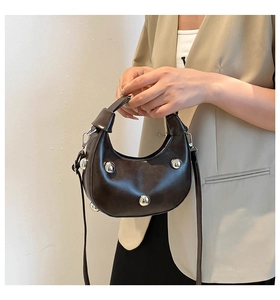 Detail of dark brown hobo bag with large silver polished metal studs and crossbody strap