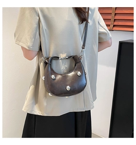 Macro shot of dark brown crescent moon bag featuring silver rivets and adjustable strap