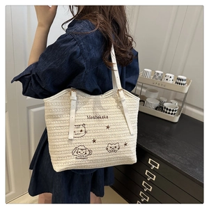 Detail of white woven tote bag with cat embroidery and faux leather shoulder strap