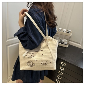 Straw tote bag detail with cute cat embroidery and comfortable white shoulder straps