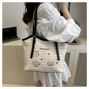 Détail du sac cabas en paille tressée avec broderie chat noir et anses en cuir