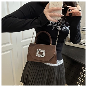 Détail d'un sac en daim marron avec boucle carrée en cristal et fine chaîne dorée