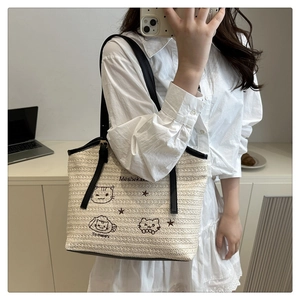 Straw tote bag with cute cat embroidery and black leather straps shown in a mirror selfie