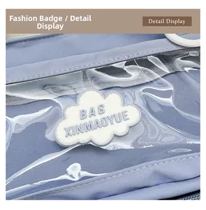 Detail of light blue shoulder bag featuring transparent PVC pocket and cloud badge