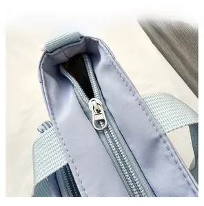 Close-up detail of smooth silver metal zipper and woven strap on light purple nylon backpack