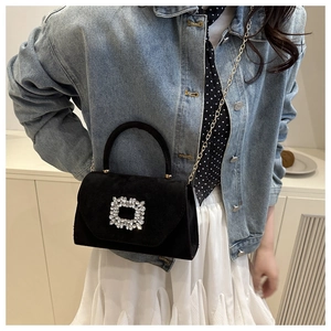 Détail d'un sac à bandoulière en daim noir avec boucle carrée en strass et chaîne dorée
