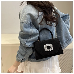 Gros plan d'un sac bandoulière en daim noir avec boucle en cristal et chaîne dorée