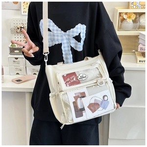Close-up of white canvas ita bag showing transparent PVC window and multi-pocket details