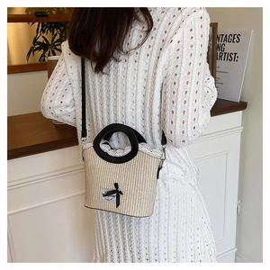Detail of woven straw bucket bag with white lace trim and black bow decoration