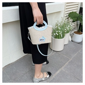 Detail of woven straw bag featuring delicate lace trim and light blue bow accent