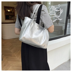 Silver minimalist tote bag with bow detail shown in a street style lifestyle setting