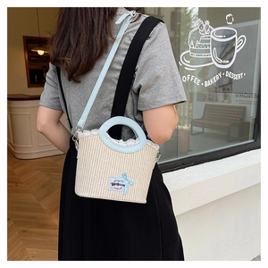 Détail du sac seau en paille avec anses en cuir bleu clair et nœud en dentelle