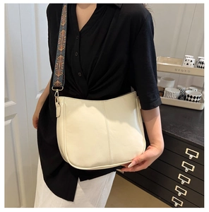 Detail of cream crossbody bag with vintage embroidered wide strap on a model