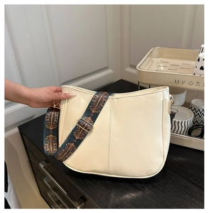 Detail of cream half-moon crossbody bag with geometric pattern wide woven strap