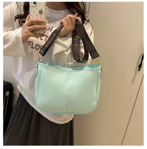 Detail of mint green crossbody bag featuring a wide ethnic embroidered shoulder strap