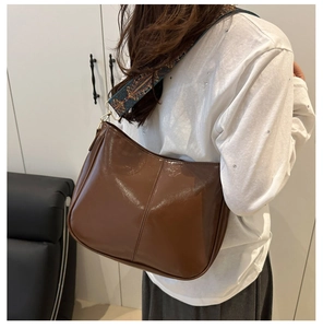 Detail of glossy brown shoulder bag with a vintage bohemian floral wide strap
