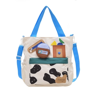 Cute cow print canvas tote bag for students with blue handles and a mini coin purse charm