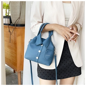 Close-up of a blue shirt-style handbag featuring a collar design and metal button detail