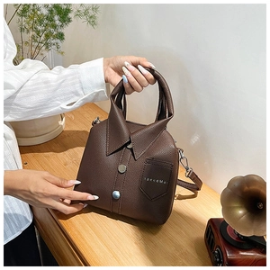 Detailed view of coffee brown litchi leather handbag with shirt collar design elements