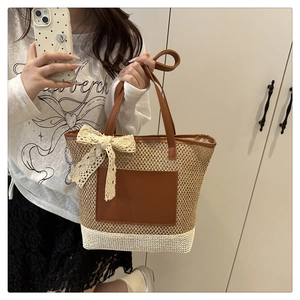 Détail d'un sac cabas en paille tissée avec patch cuir marron et nœud en dentelle