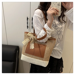 Détail d'un sac cabas en paille tissée avec empiècement en cuir brun et nœud en dentelle