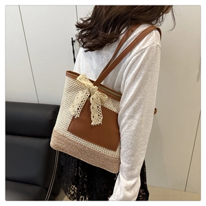 Close-up of woven straw tote bag featuring leather pocket and cream lace bow detail