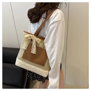 Detail of woven straw bucket bag with brown leather straps and cream lace bow detail
