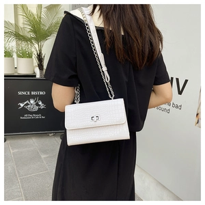 Detailed view of crocodile embossed white chain bag with silver twist lock on a model
